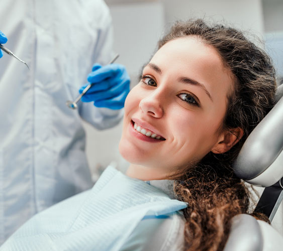 smiling woman in a dentist's chair during treatment