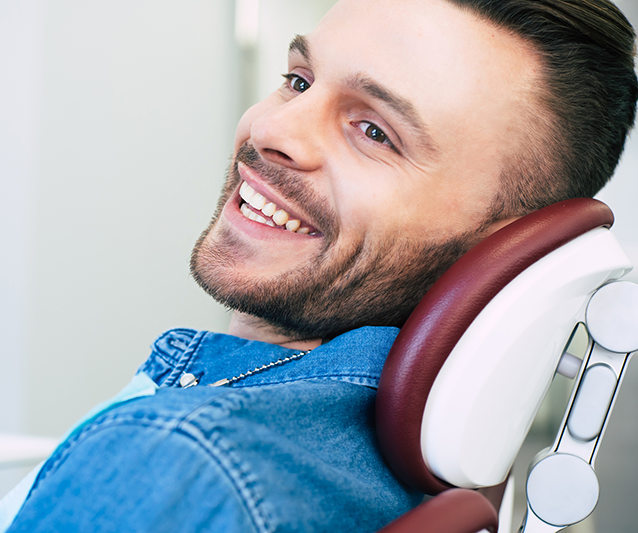 A male patient in a dental chair smiles after a same-day dental treatment